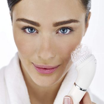 mujer limpiando el rostro con cepillo facial y jabon