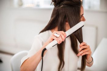 chica alisandose el pelo con plancha