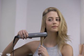 chica rubia planchando el pelo