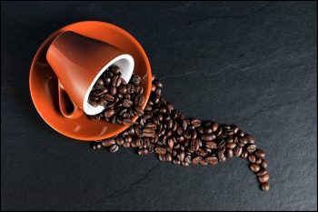 granos de cafe en una taza derramandose