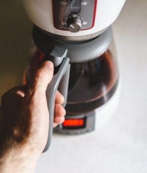 mano cogiendo cafetera de goteo