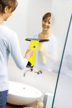 mujer limpiando espejos y mamparas del baño