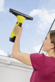 mujer limpiando ventana inclinada con una aspiradora