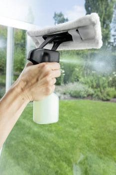 usando detergente y paño de microfibra para limpiar ventanas