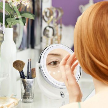 mujer mirandose en espejo de maquillaje redondo