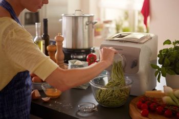 mujer haciendo pasta con una maquina de hacer pasta automatica