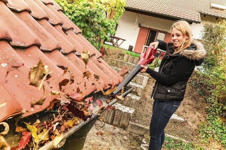 chica usando soplador de hojas en un tejado