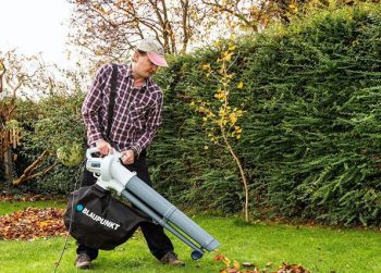 hombre aspirando hojas del jardin