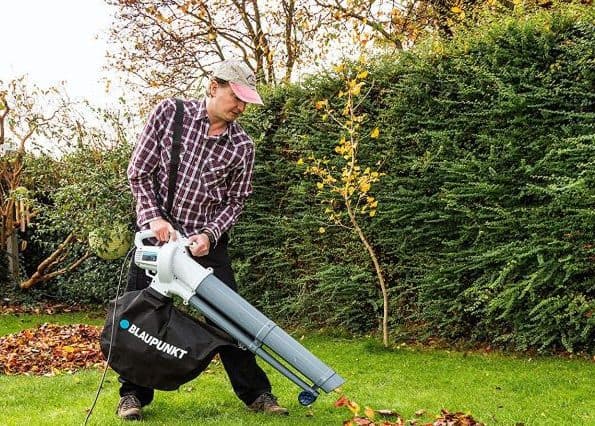 hombre aspirando hojas del jardin