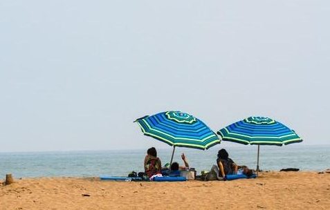 personas en la playa bajo una sombrilla