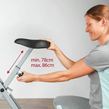 Bicicletas estáticas: Guía para comprar la mejor de 2019 imagen 6 mujer ajustando la altura del sillín de bicicleta estática