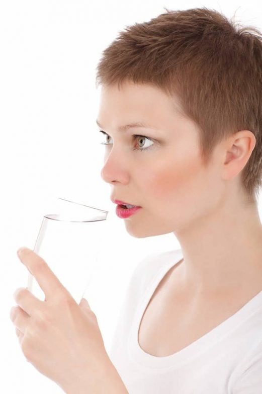 mujer bebiendo agua del grifo filtrada