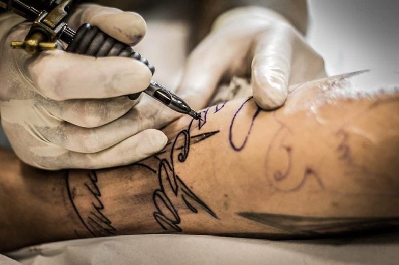 haciendo un tatuaje en el brazo con crema para tatuajes anestésicas
