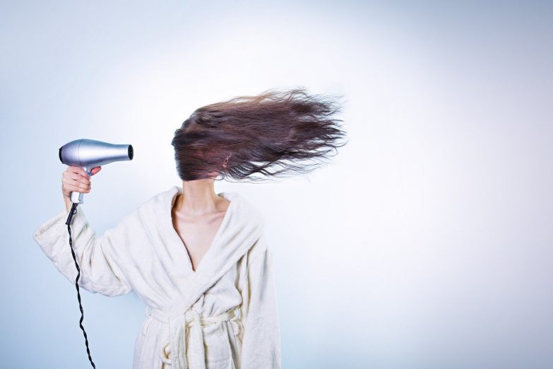 mujer usando secador de pelo a máxima potencia