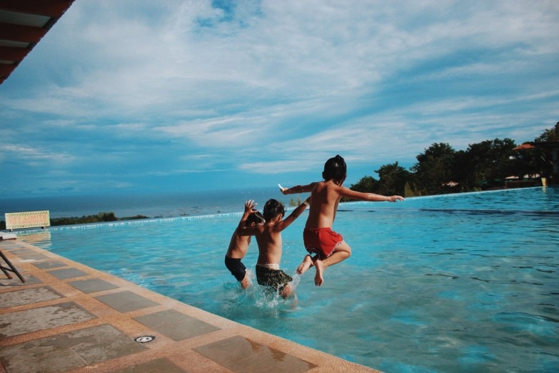 Niños entrando en la piscina después del uso de un robot limpiafondos