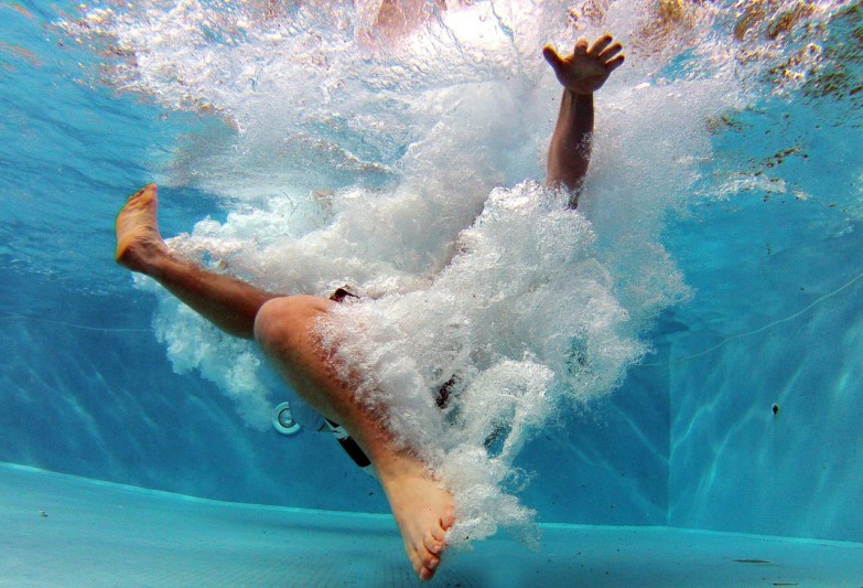 Zambullida en la piscina después de poner en funcionamiento un robot limpia piscinas adecuadamente