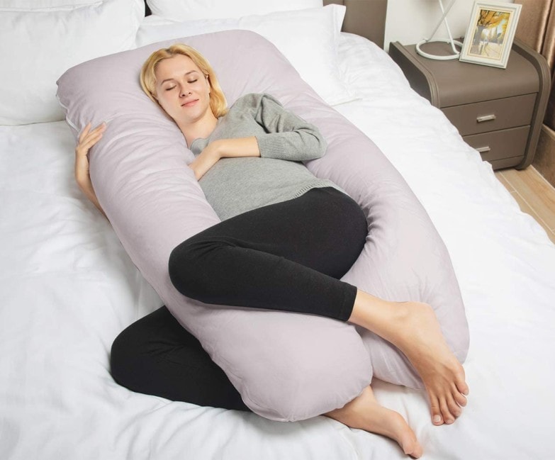 Mujer joven usando una almohada de lactancia para dormir