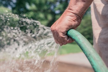 Hombre sosteniendo una manguera de agua conectada a una hidrolimpiadora