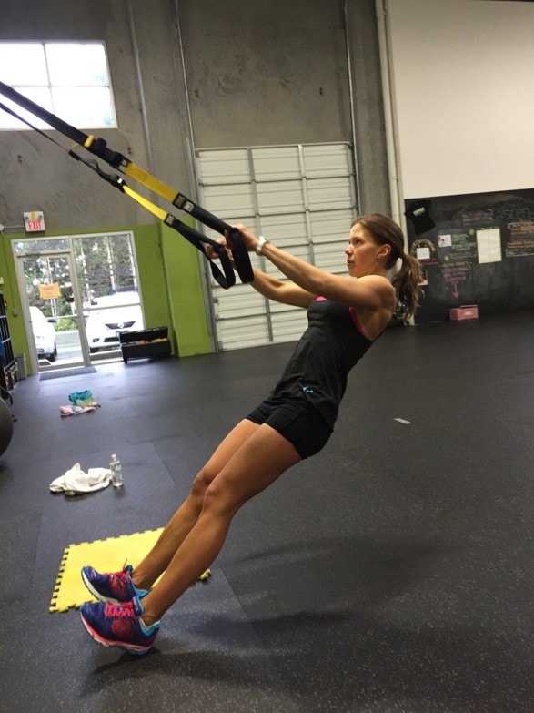 chica profesional usando cintas trx para entrenar