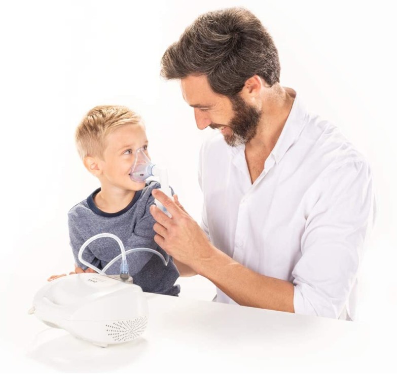 Hombre sosteniendo una mascarilla pediátrica de un nebulizador en el rostro de un niño