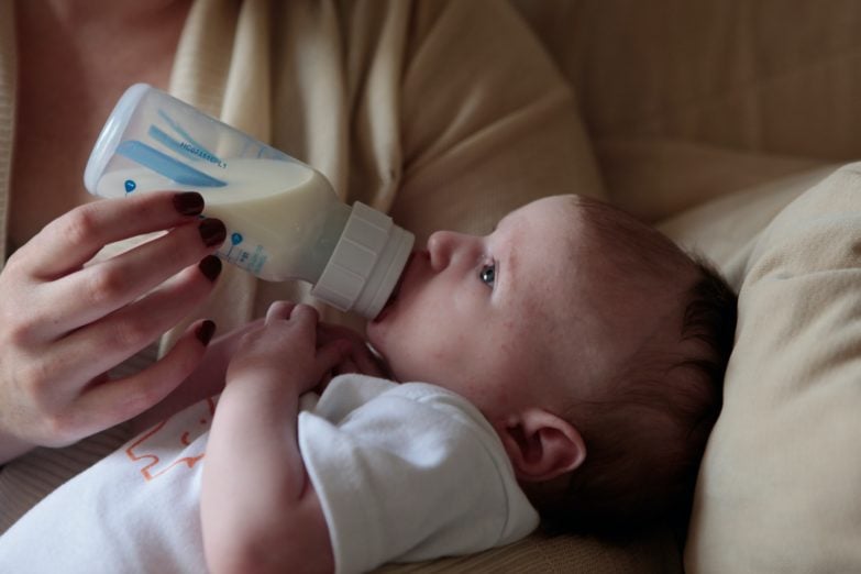 Bebé tomando leche de un biberón calentado en un calienta biberones