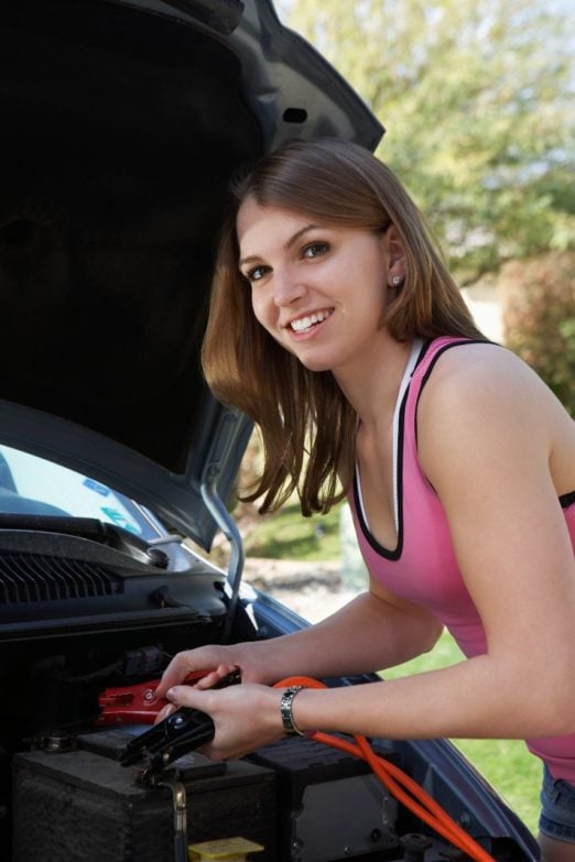 chica usando arrancador de batería para coche