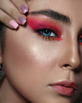 Mujer de ojos azules maquillada con sombra roja brillante