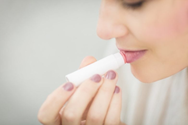 mujer aplicándose en sus labios un exfoliante labial