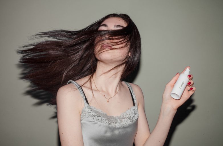 mujer sacudiendo el cabello después de aplicarse champú seco