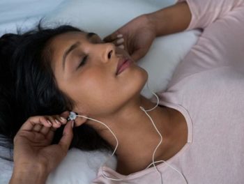 Mujer usando audífonos en una máquina de ruido blanco para dormir