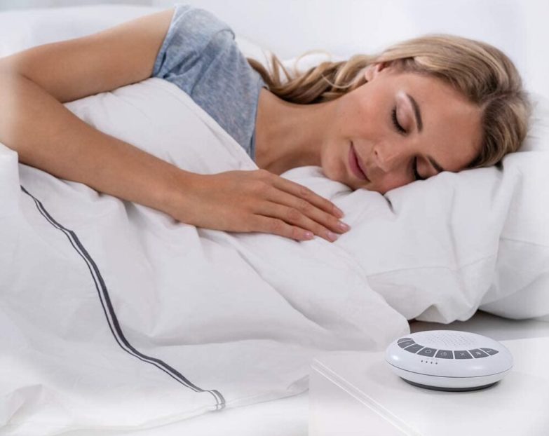mujer durmiendo y máquina de ruido blanco en la mesita de noche