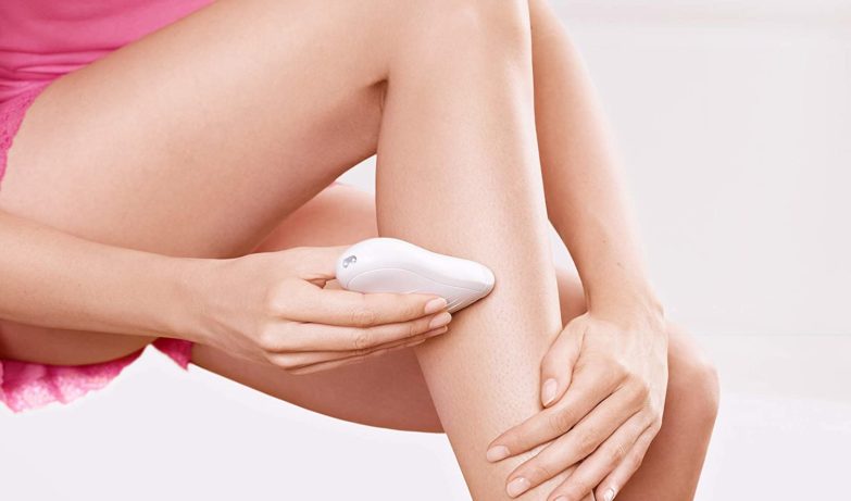 mujer depilándose las piernas con una máquina depiladora eléctrica
