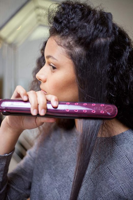 mujer planchando su cabello rizado con una plancha de pelo Rowenta