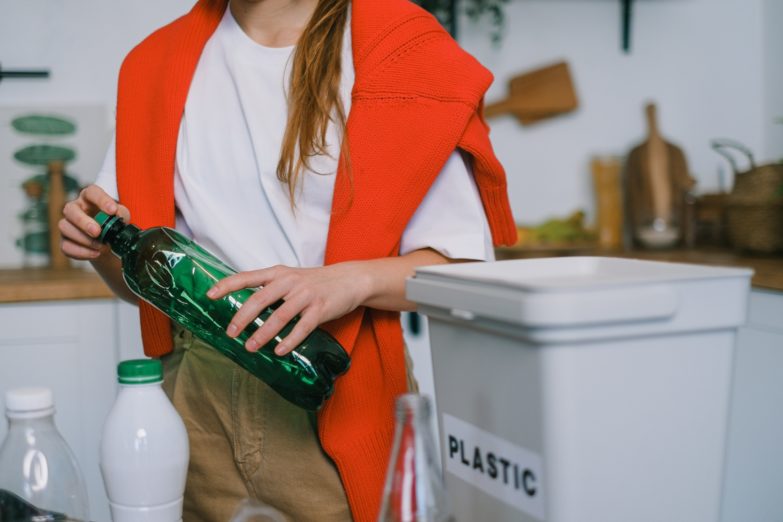 Los mejores cubos de basura de reciclaje para casa imagen 1 Mujer reciclando plástico en cubos de basura de reciclaje
