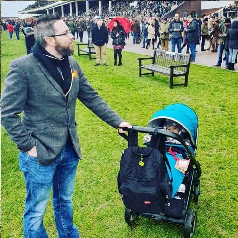 Hombre llevando un carrito de bebé con una mochila colgada