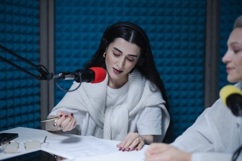 mujeres en una cabina de radio usando un brazo para micrófono