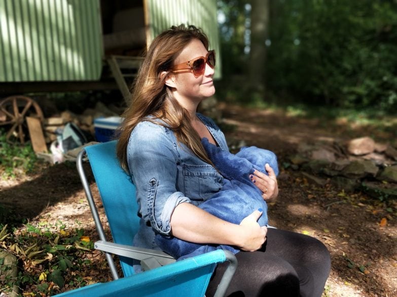 mujer sentada en un sillón de lactancia al aire libre amamantando a un bebé