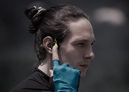 Hombre escuchando por auricular óseo después de elegir los mejores auriculares de conducción ósea