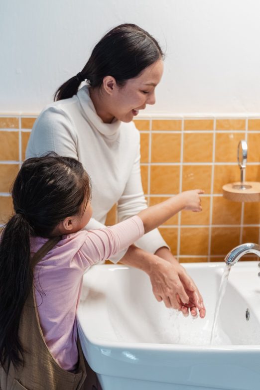 mujer y niña lavándose las manos en el lavabo