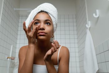 mujer limpiando su rostro antes de usar una máscara de luz LED facial