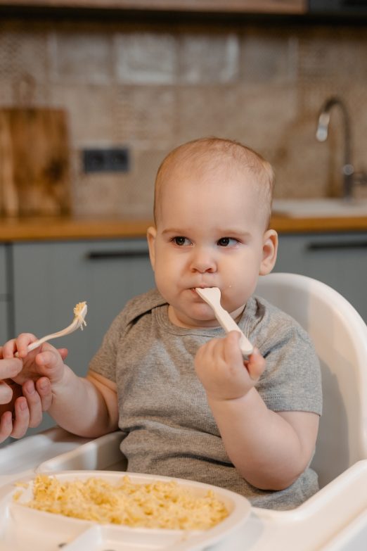bebé comiendo alimentos sólidos sentado en una trona para bebés