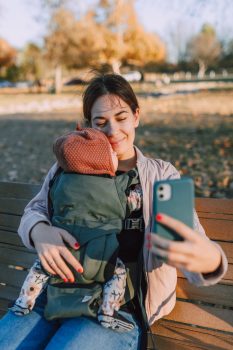 mujer tomándose un selfie con su bebé porteado en una mochila