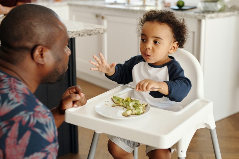 niño comiendo sentado en una trona para bebés