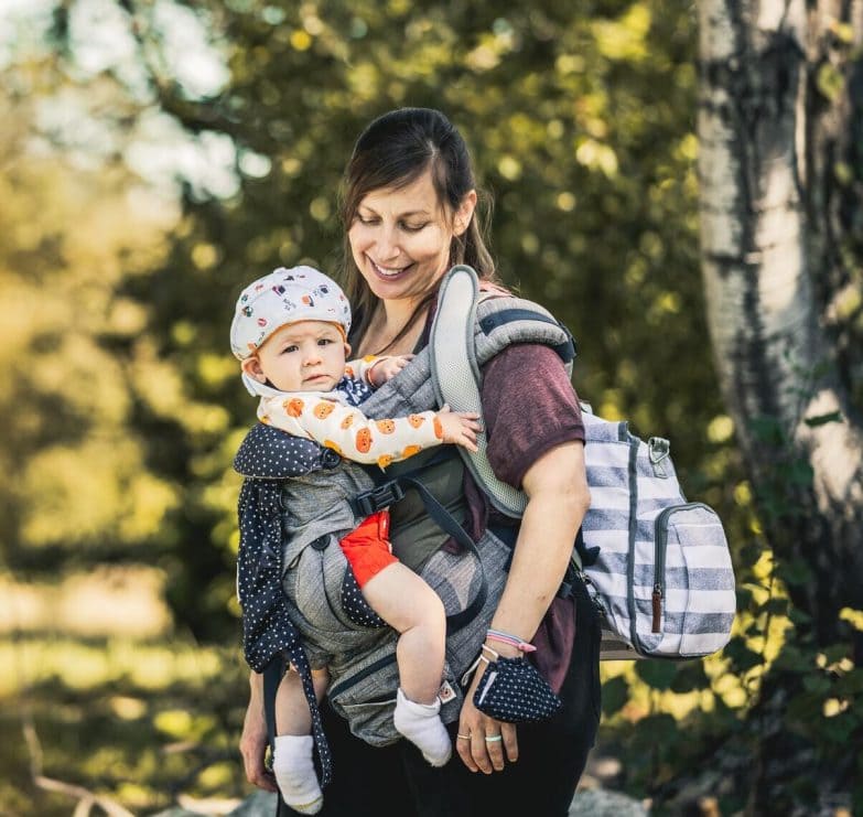 mujer porteando a un bebé de 6 meses en una mochila portabebés 