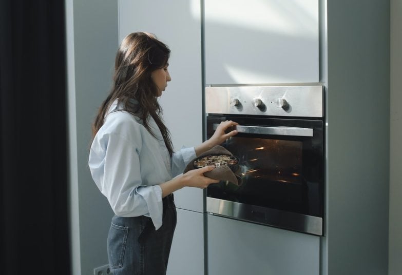Mujer cocinando con horno eléctrico