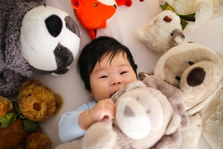 evitar llenar la casa de juguetes y un bebé rodeado de peluches