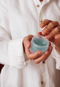 persona mostrando un bote de gel para el pelo