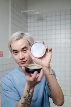 hombre mostrando un bote abierto de cera para el cabello