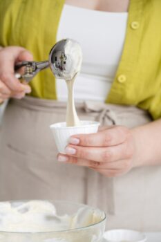 sirviendo el helado en un vasito con una cuchara para helados
