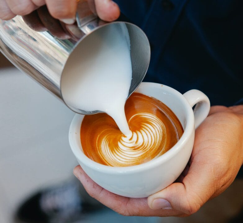 vertiendo espua deleche en una taza de café